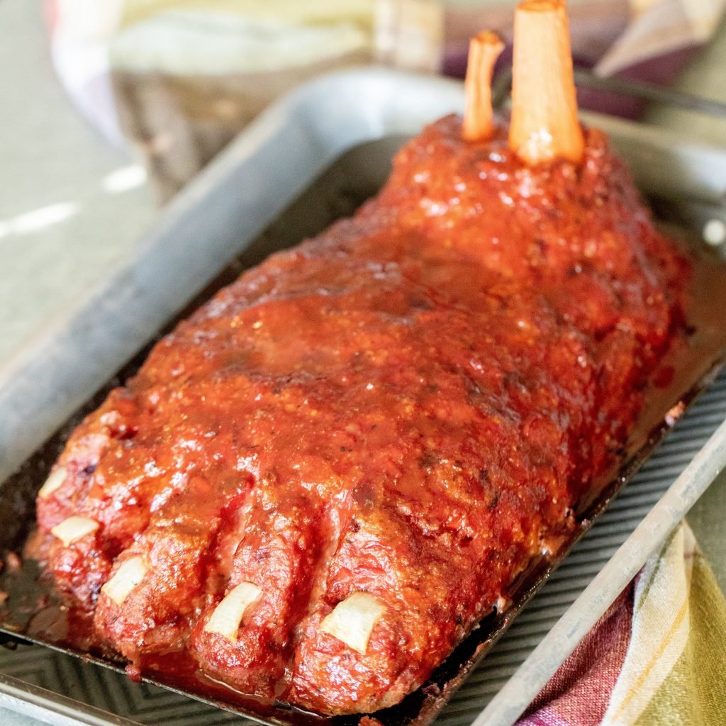 Large meat loaf shaped like a foot in a metal baking tray.