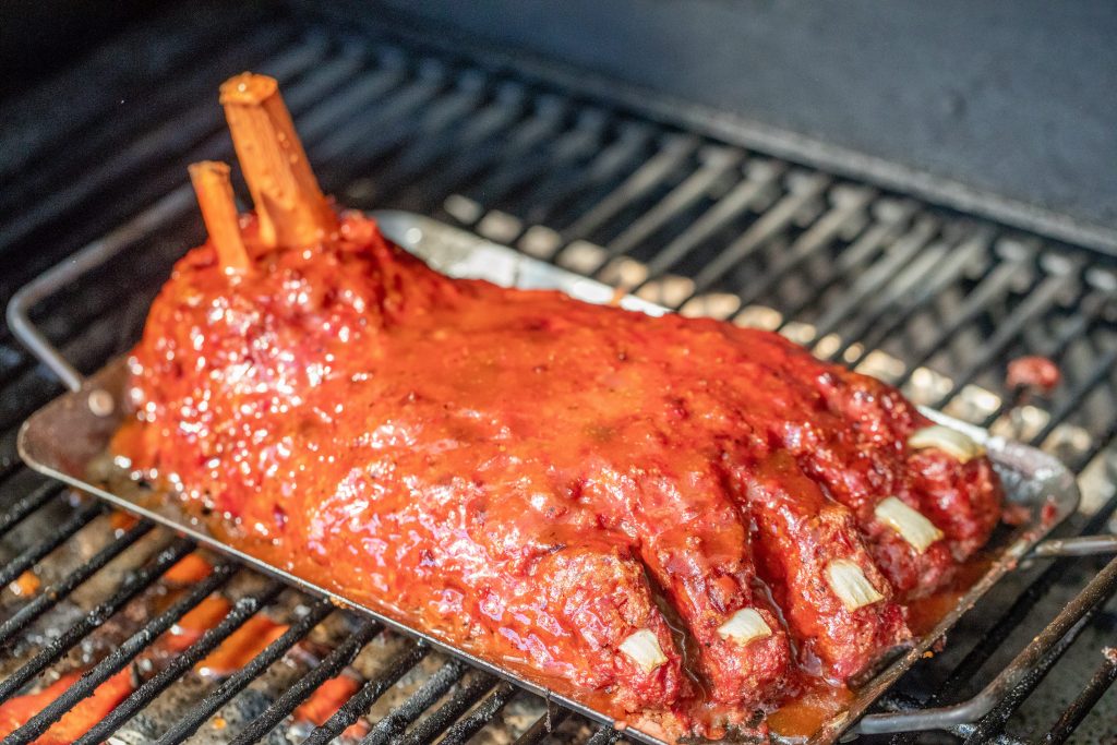 large meatloaf shaped like a foot, on a tray inside the grill.