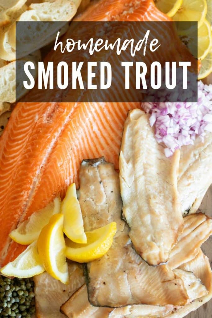 smoked trout filets with lemon wedges, red onions, and capers on a wood board.