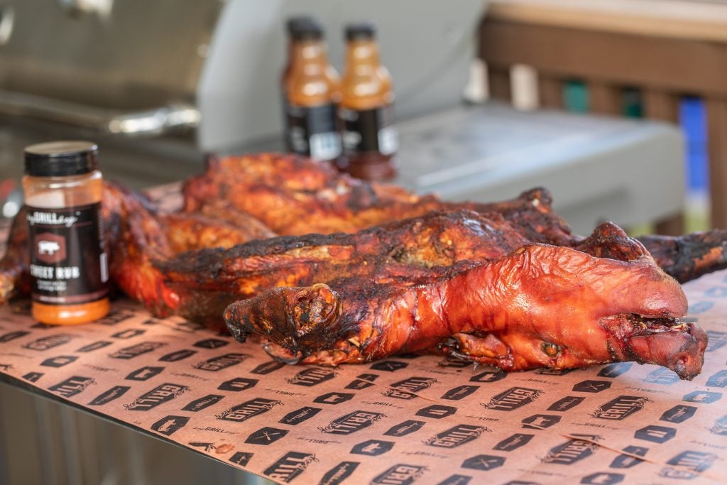 smoked pig on a table with bottles of BBQ seasoning and BBQ Sauce.