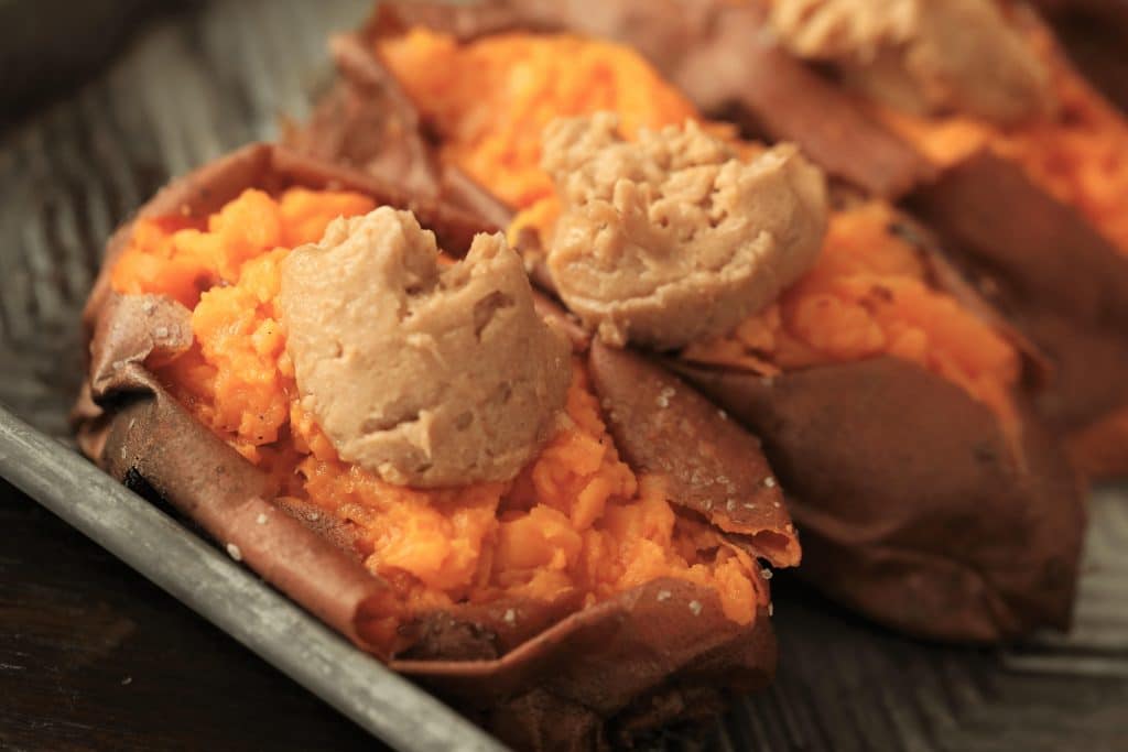two smoked sweet potatoes each with a spoonful of maple cinnamon butter.