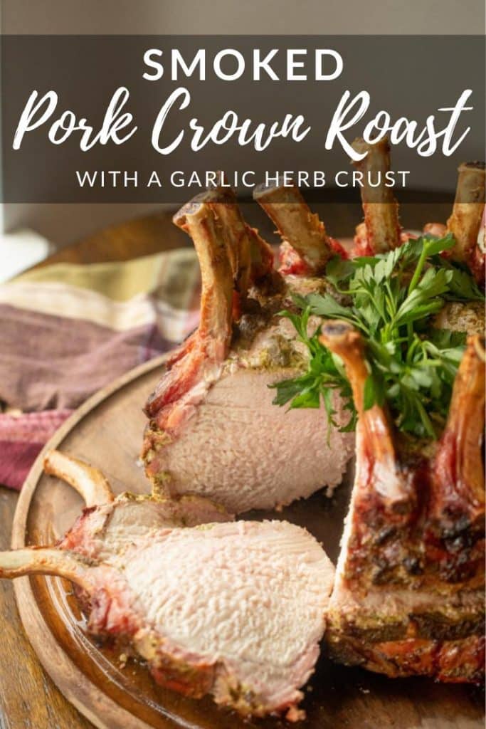 Smoked Pork Crown Roast on a wooden cutting board with two slices cut out and resting next to the roast.