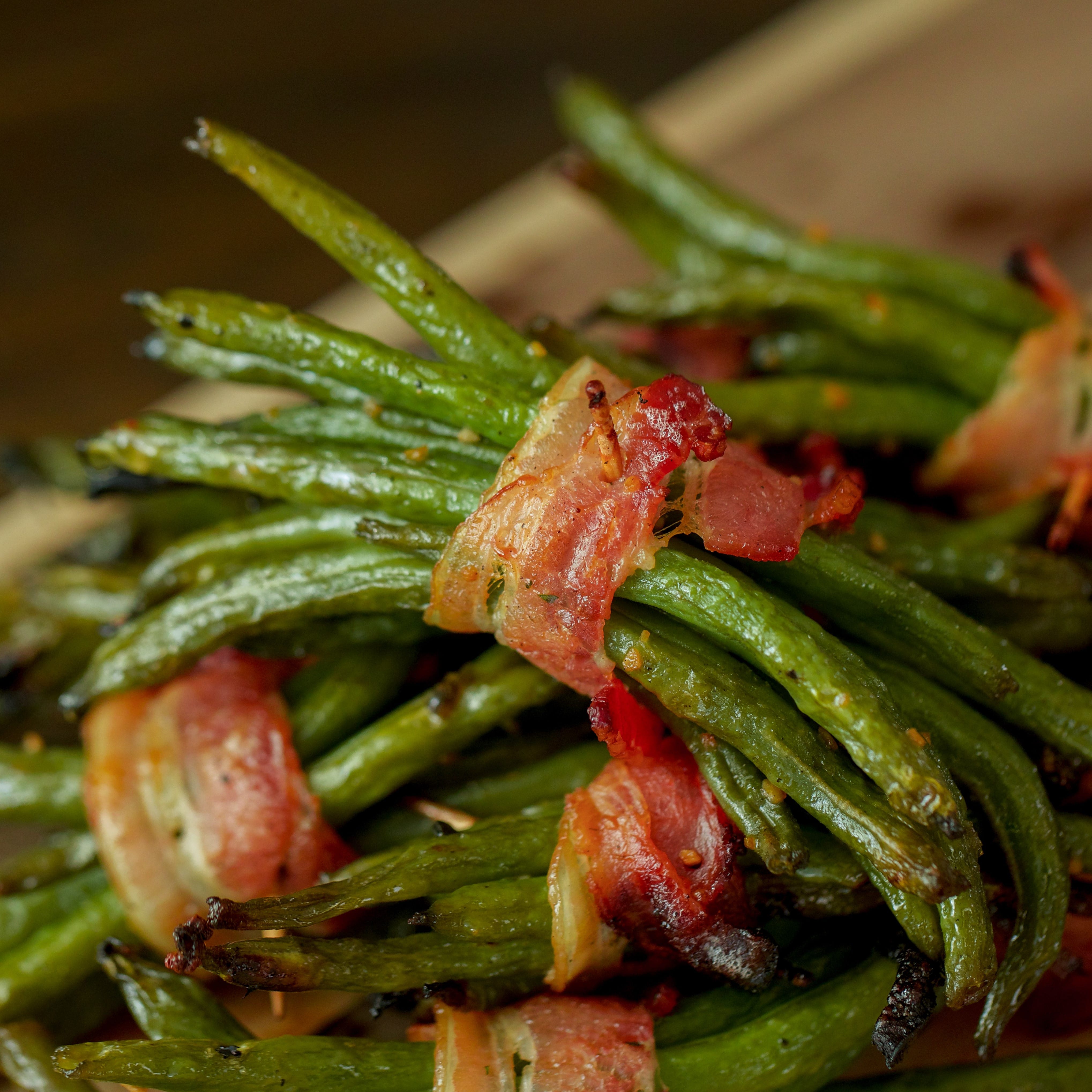 Bacon Wrapped Green Bean Bundles in a stack on a wooden cutting board