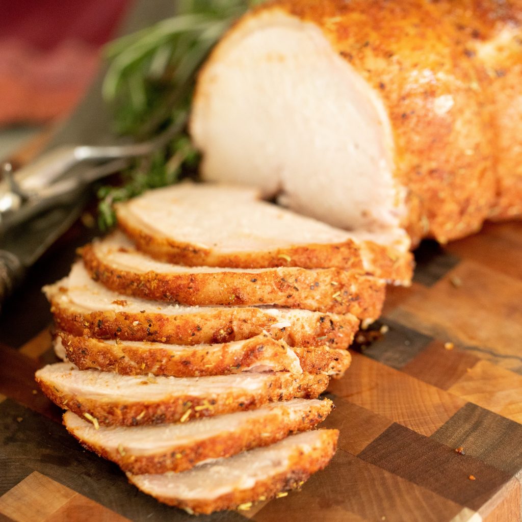 Smoked and sliced cider brined turkey breast lined up on a wooden cutting board.
