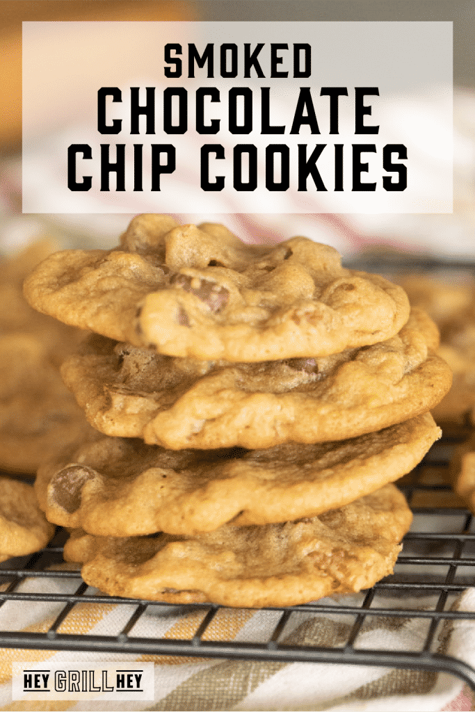 Four smoked chocolate chip cookies stacked on a metal cooling rack with text overlay - Smoked Chocolate Chip Cookies.
