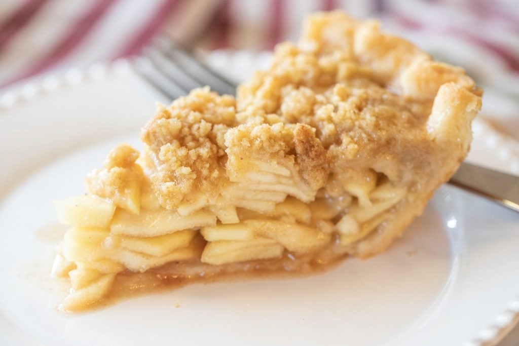 A slice of Dutch apple pie on a white plate