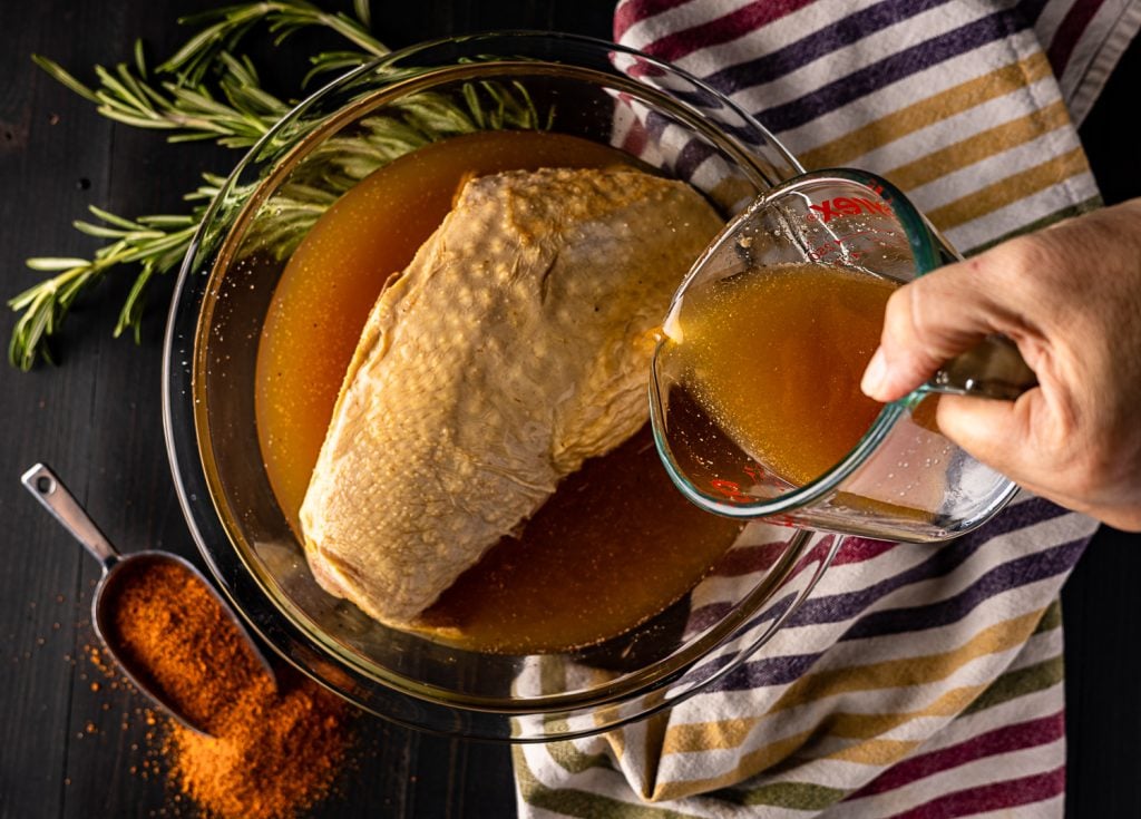 Apple cider being poured over a turkey breast.