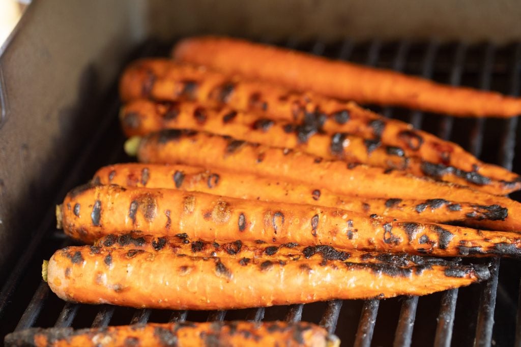 seasoned carrots with blackened grill marks on a gas grill.