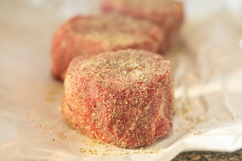 three filet mignon steaks seasoned with beef rub on butcher paper.