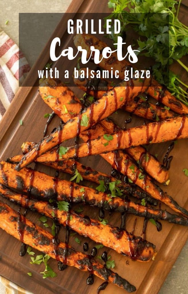 grilled carrots drizzled with balsamic glaze on top of a wooden cutting board.