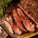 Sliced flank steak on a cutting board.