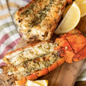 Grilled lobster tail on a wooden cutting board.