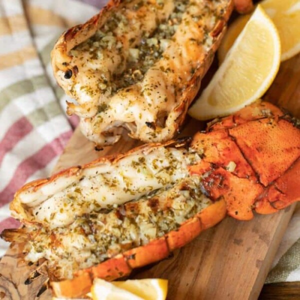 Grilled lobster tail on a wooden cutting board.