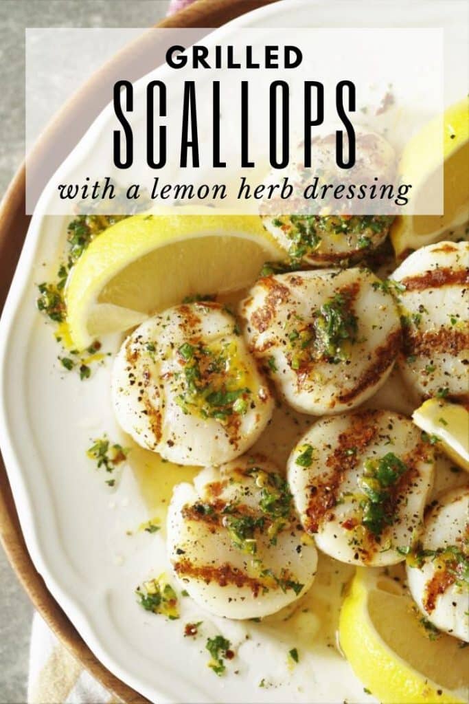 plate of grilled scallops drizzled with a lemon herb dressing with lime wedges.