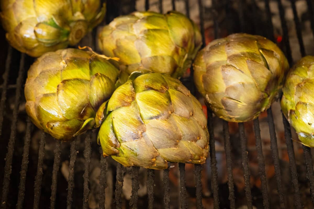 Artichoke halves on the grates of a grill.