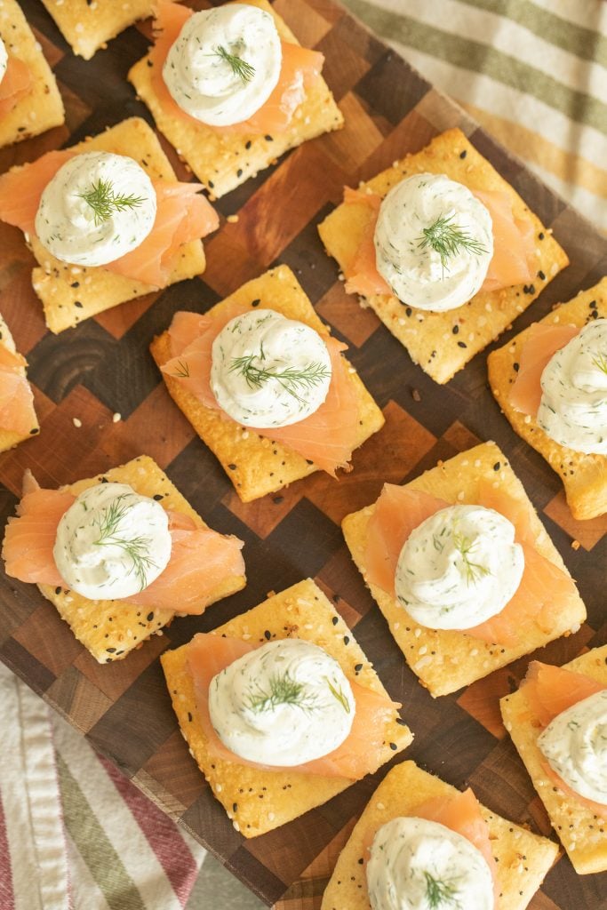 wooden cutting board arranged with a dozen smoked salmon appetizers.