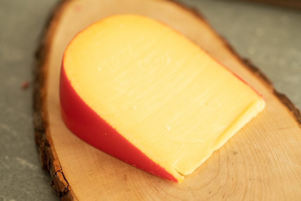 smoked gouda cheese on a wooden cutting board.
