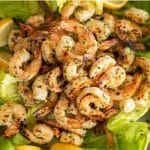 Marinated and grilled shrimp piled on a bed of lettuce and sliced lemons.