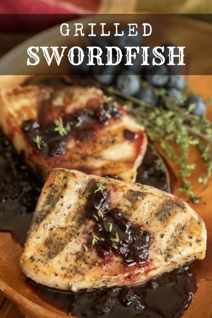 two grilled swordfish fillets topped with a blueberry balsamic reduction in a wooden bowl.
