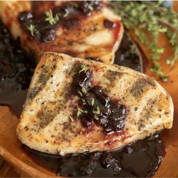 Two whole grilled swordfish fillets drizzled with a blueberry balsamic reduction.