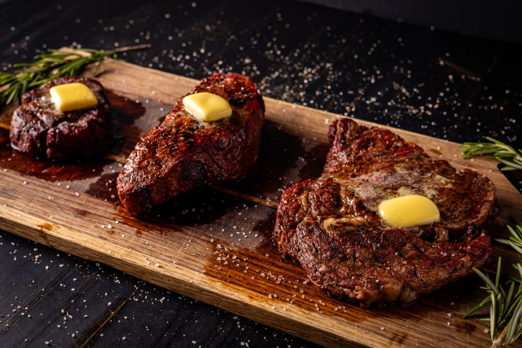 Grilled steaks on a wooden cutting board.