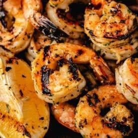 Marinated shrimp piled next to lemon wedges.