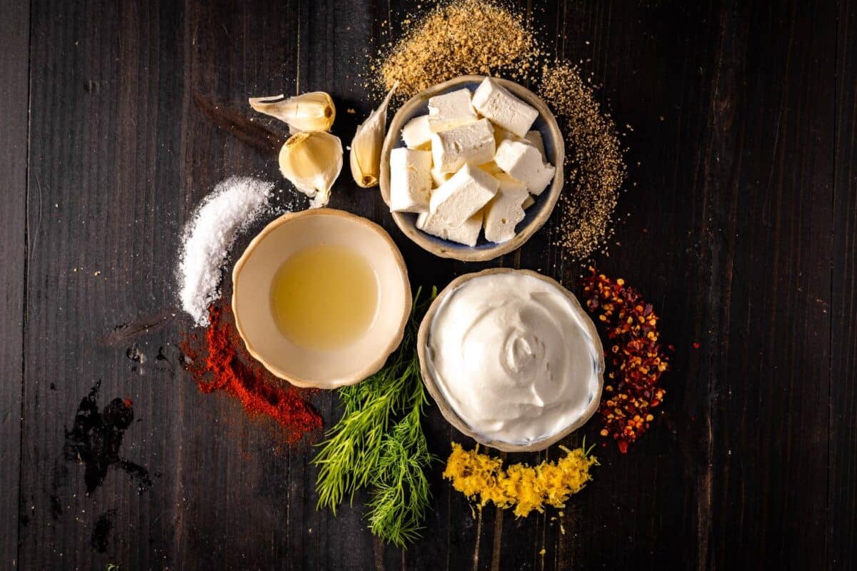 Bowls with cream cheese, butter and oil, on a counter with raw spices.