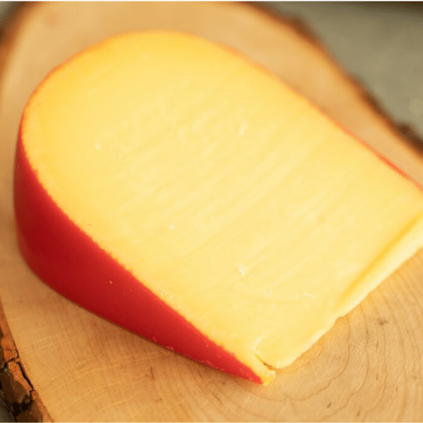 Wedge of smoked gouda on a wooden board.