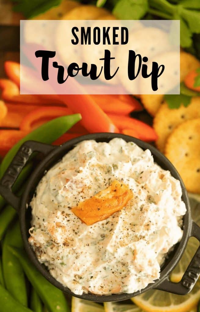 container of smoked trout dip surrounded by fresh sliced vegetables and crackers.