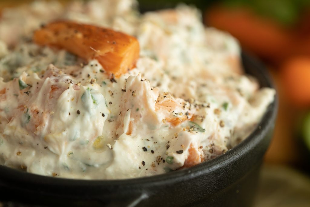close up of smoked trout dip in a black serving dish.