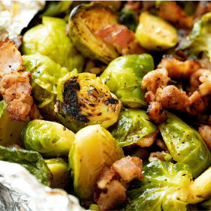 grilled brussels sprouts topped with chunks of bacon. 