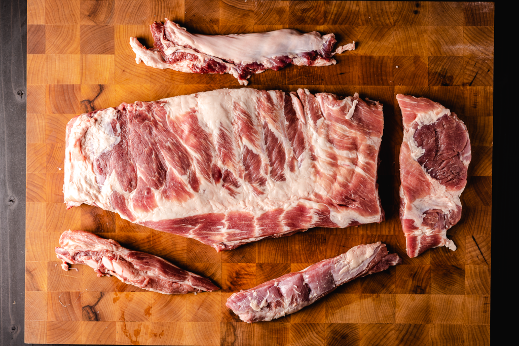 Spare ribs being trimmed on a cutting board.