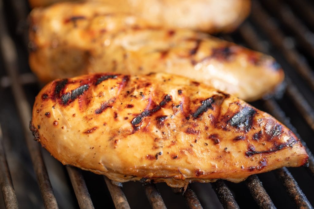 Close up of marinated grilled chicken breast on the grill.