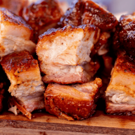 Pile of cubed pork belly on a wooden cutting board.