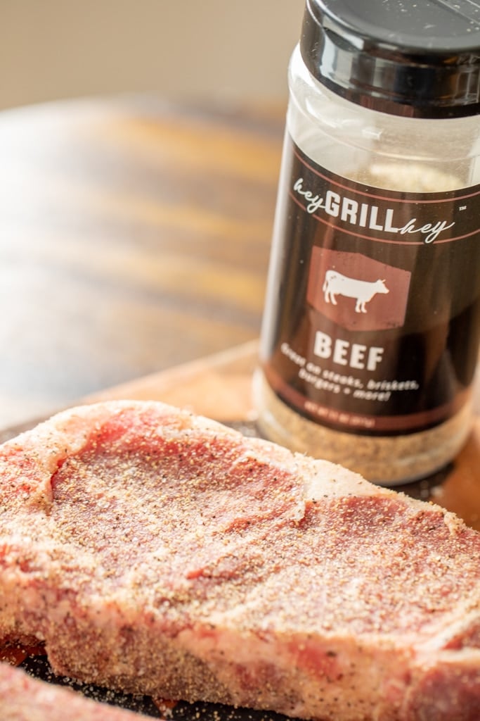NY strip steak seasoned with Beef Seasoning on a wooden cutting board.