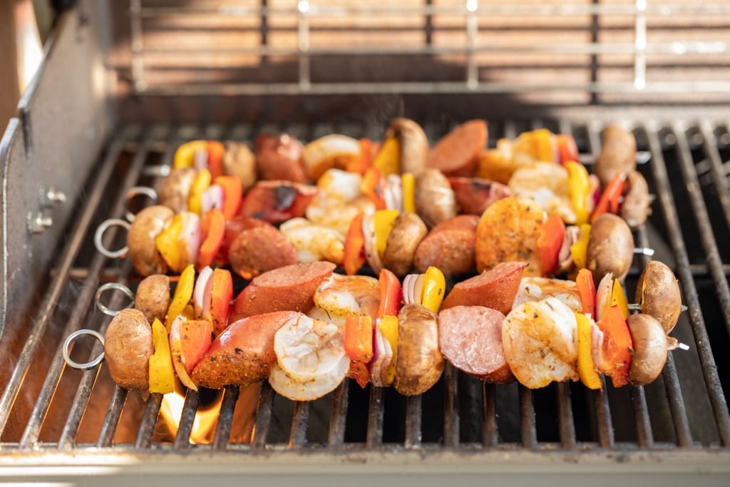 5 shrimp and sausage kabobs on a gas grill.