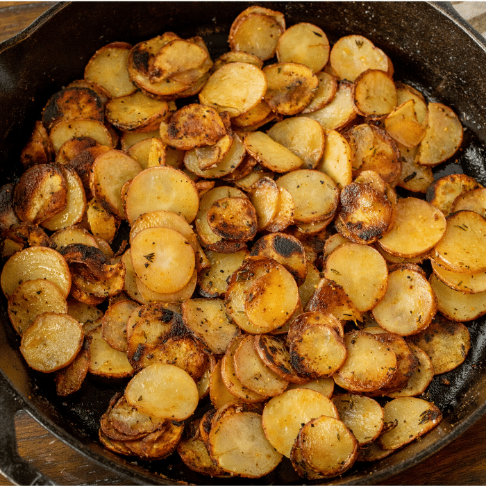baked sliced potatoes in a large black pan.