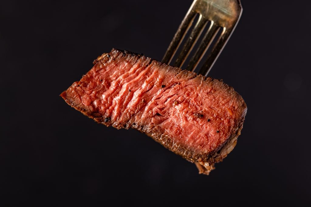 Medium rare steak on a fork.