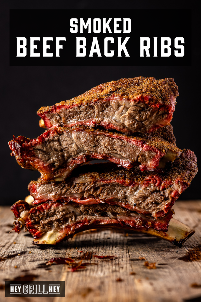 Stack of sliced beef back ribs on a cutting board with text overlay - Smoked Beef Back Ribs.