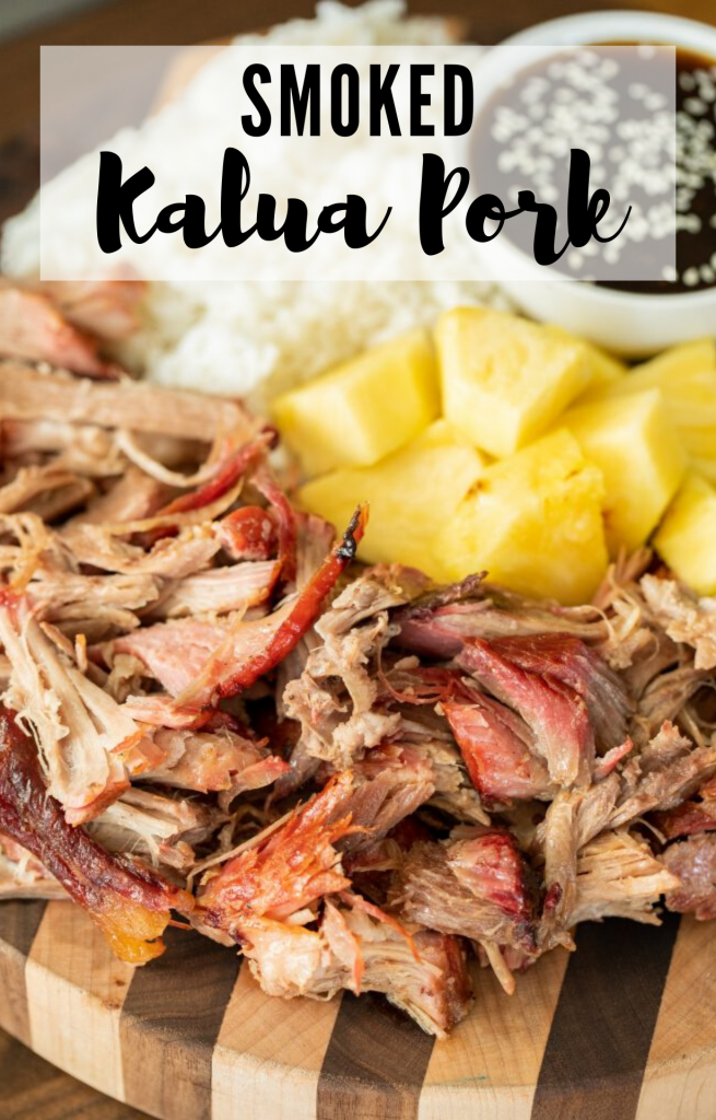 Vertical image of shredded smoked kalua pork arranged on a wood cutting board with pineapple chunks, rice, and a bowl of teriyaki sauce in the background. Decorative text says "smoked kalua pork"