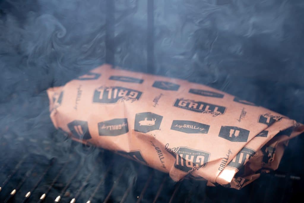 Kalua pork wrapped in pink butcher paper in a smoker