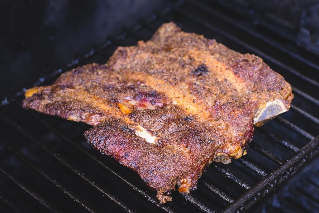 Rack of seasoned beef back ribs on the smoker.