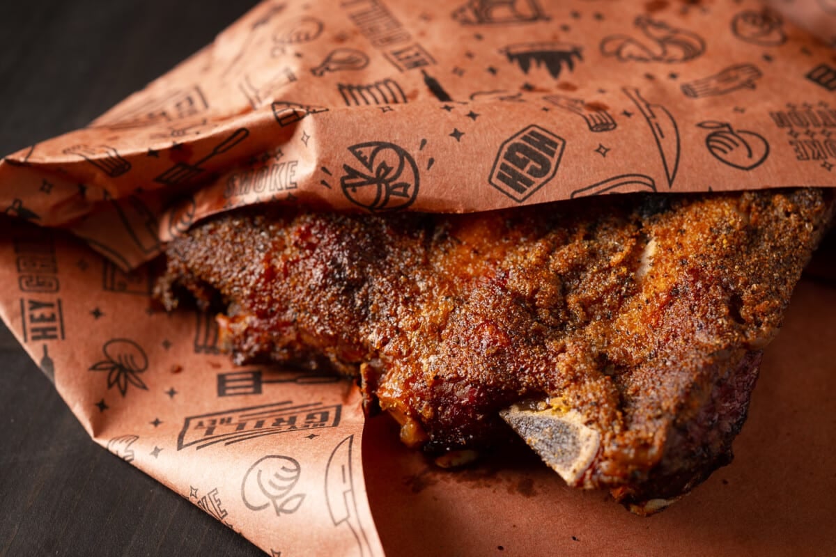 Smoked beef ribs wrapped in peach butcher paper.