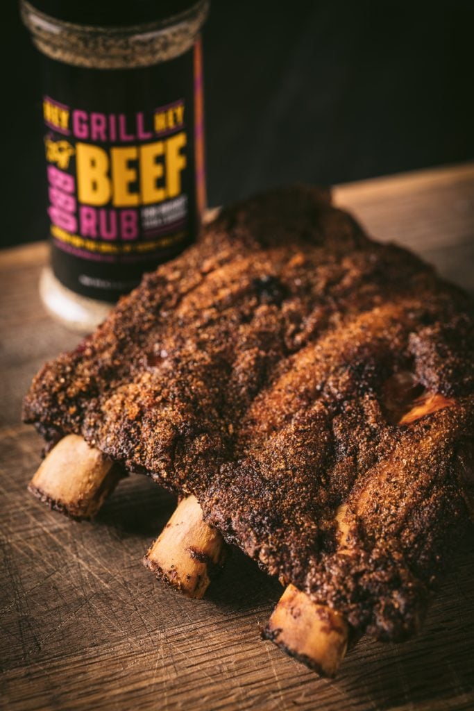 Rack of smoked beef back ribs next to a bottle of Beef Rub.