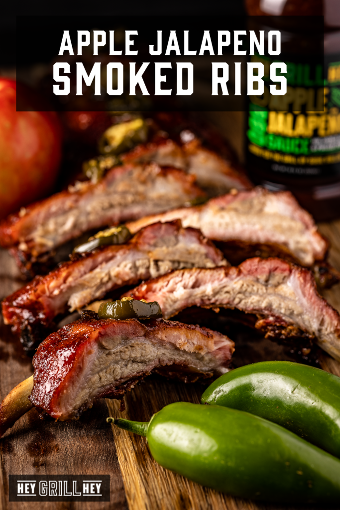 Sliced apple jalapeno ribs on a wooden cutting board next to whole jalapenos with text overlay - Apple Jalapeno Smoked Ribs.