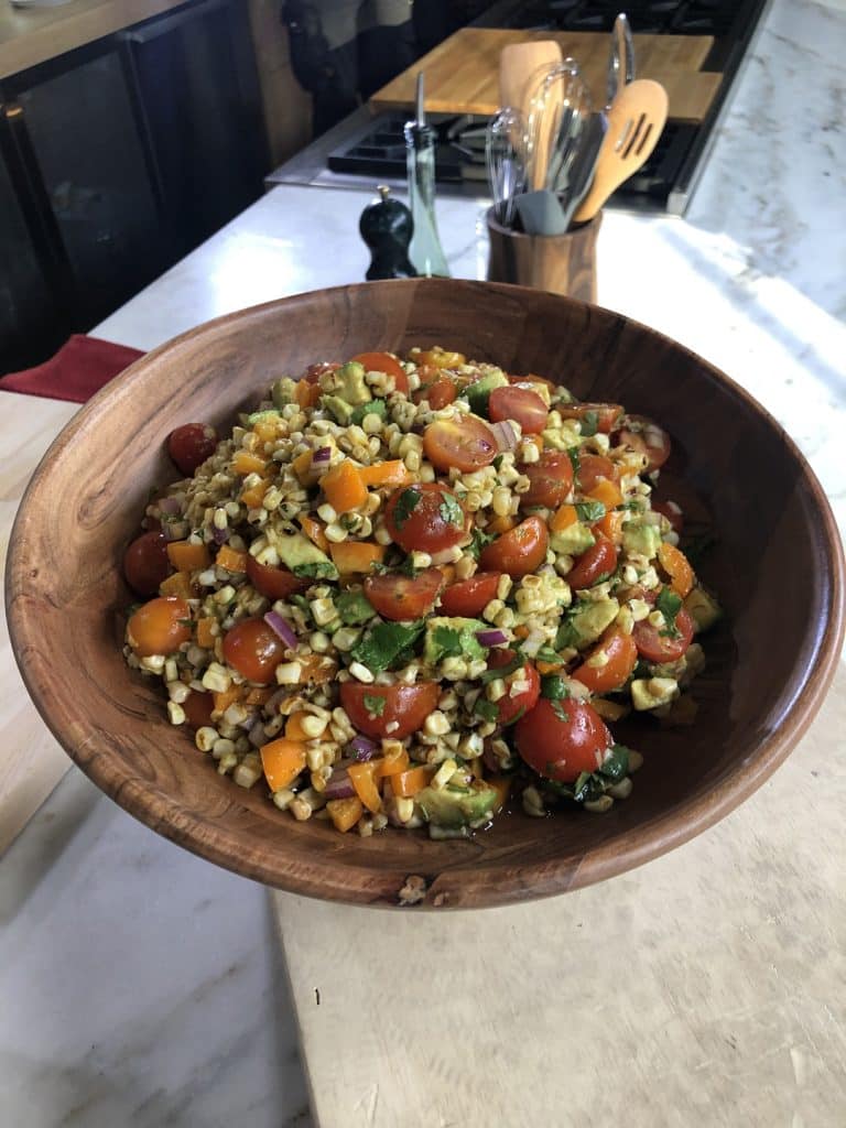A bowl of grilled corn salad on a countertop.