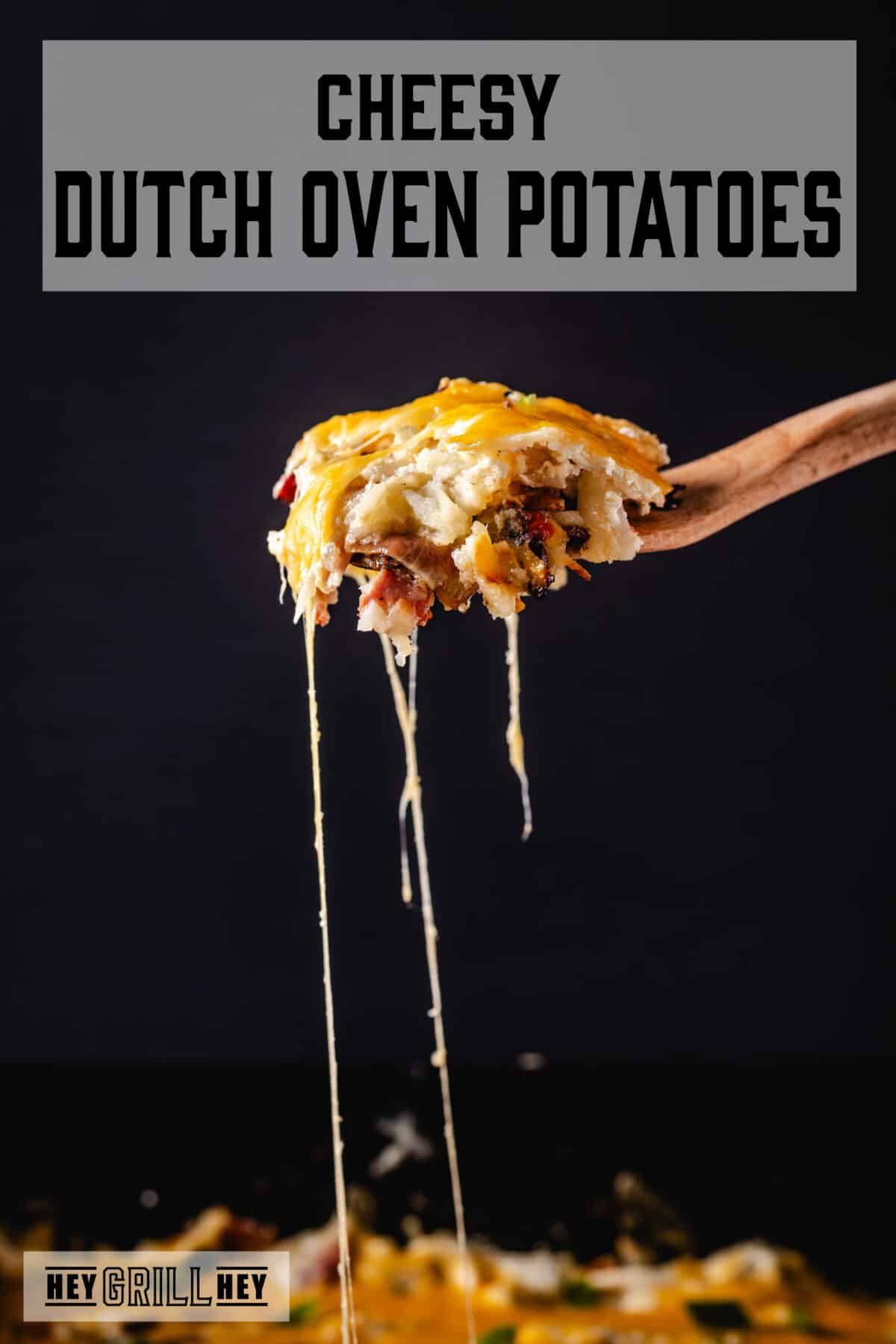 A wooden spatula holding up a scoop of Dutch oven potatoes. The text overlay reads "Cheesy Dutch Oven Potatoes" at the top, and "Hey Grill Hey" at the bottom.