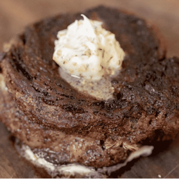A dollop of resting steak butter on top of a grilled steak.