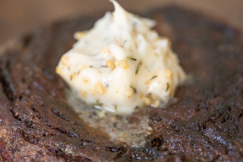 Grilled steak with a dollop of herbed butter resting atop the steak.