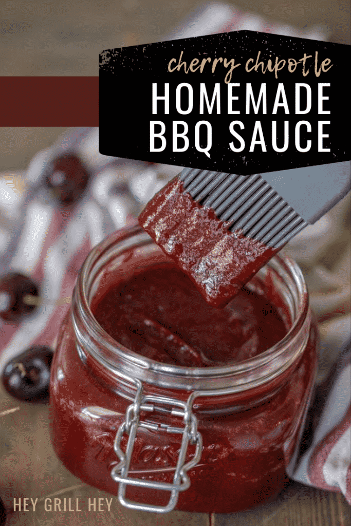 Jar of cherry chipotle BBQ sauce with a basting brush lifting out of the jar lightly coated in sauce.